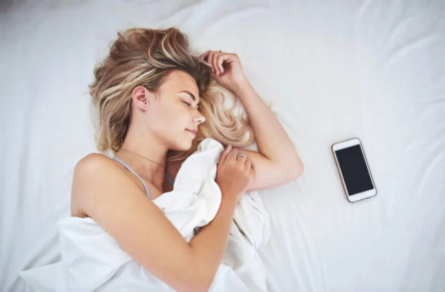 女人側睡床上有手機