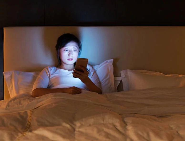 女人晚上坐在床上看手機