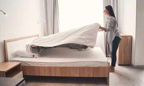 女人站在床尾整理床舖