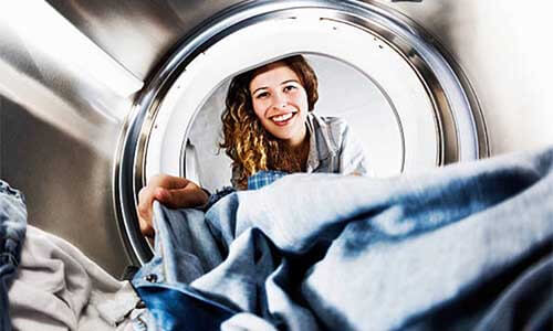 女生笑著看洗衣機內