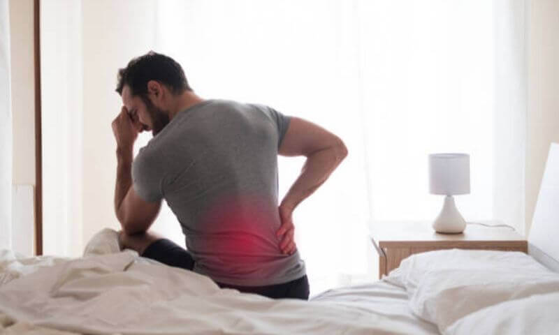 男性僵直性脊椎炎患者，坐在床上感到背痛腰痛